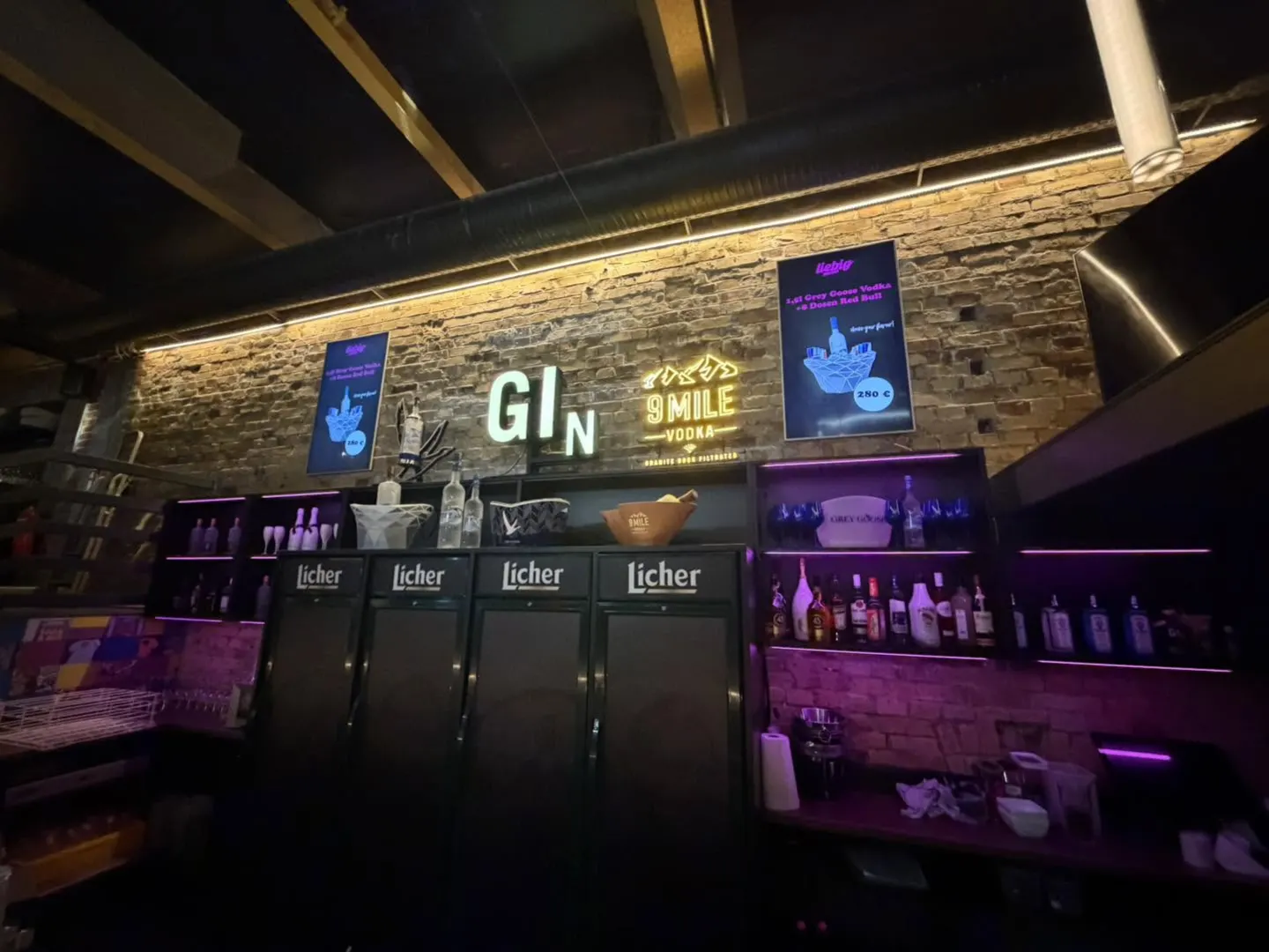 Die Bar im Liebig mit beleuchteter Backsteinwand und Kühlschränken