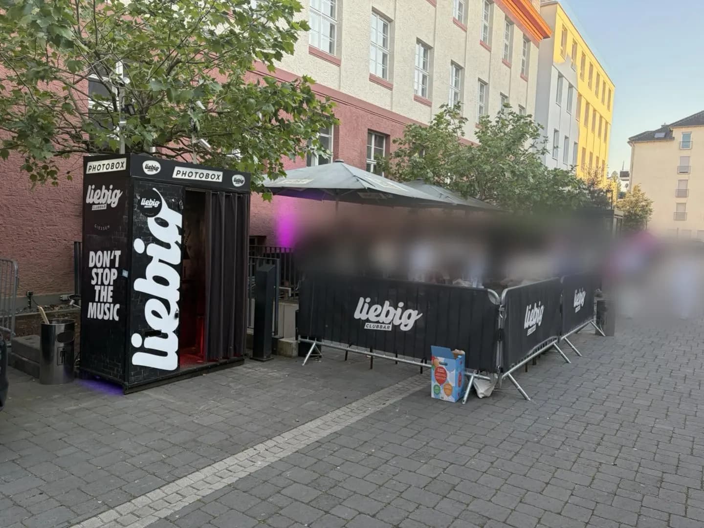 Eingang und Outdoor-Area des Liebig mit Sonnenschirmen und Liebig-Bannern
